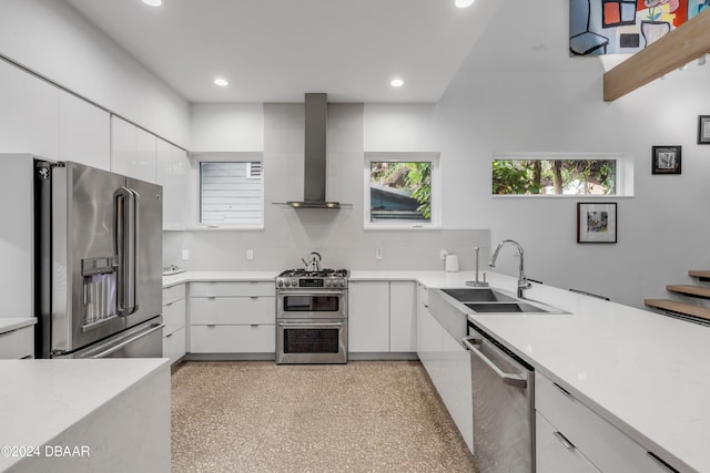 kitchen with white cabinetry, high quality appliances, wall chimney range hood, and sink