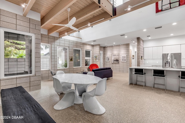 dining room featuring beamed ceiling, ceiling fan, wooden ceiling, and tile walls