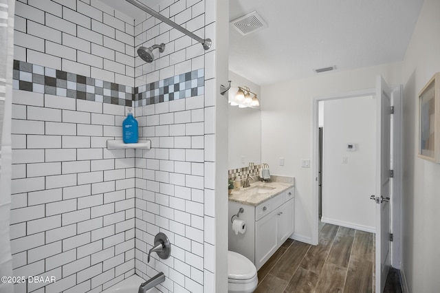 full bathroom featuring tiled shower / bath, vanity, toilet, and hardwood / wood-style floors