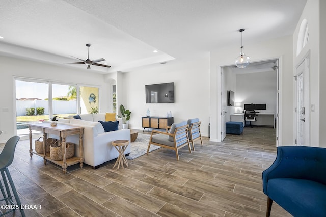 living room with a raised ceiling and ceiling fan