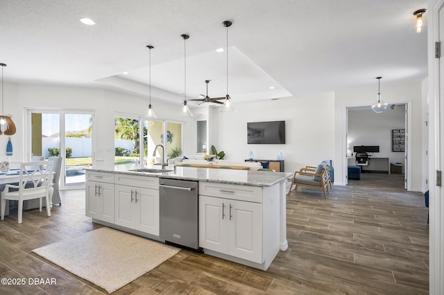 kitchen with sink, a tray ceiling, white cabinets, decorative light fixtures, and stainless steel dishwasher