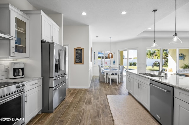 kitchen with white cabinetry, sink, light stone countertops, and appliances with stainless steel finishes