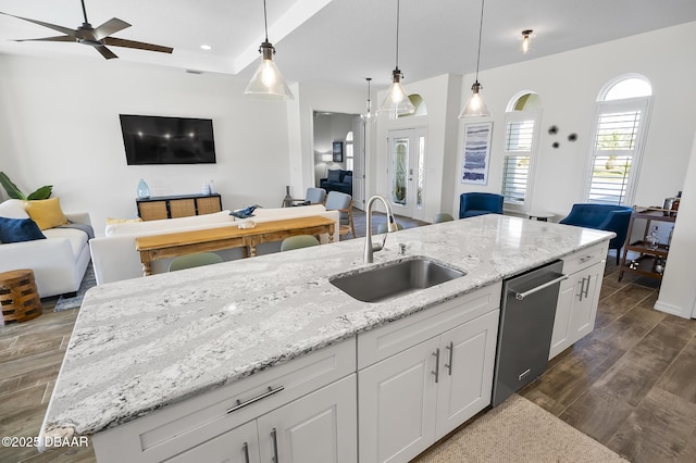 kitchen with sink, a kitchen island with sink, white cabinetry, decorative light fixtures, and stainless steel dishwasher