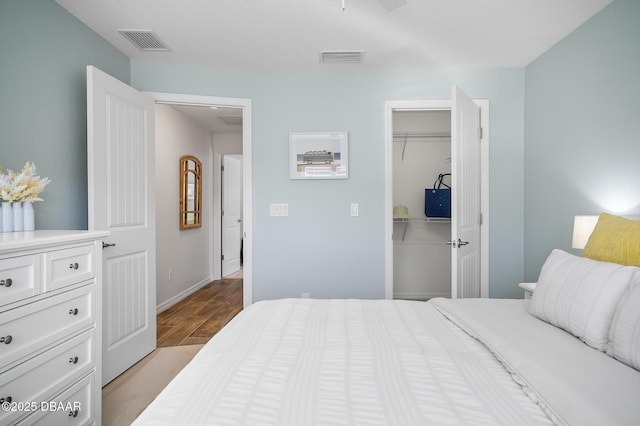 bedroom with a walk in closet, a closet, and light wood-type flooring