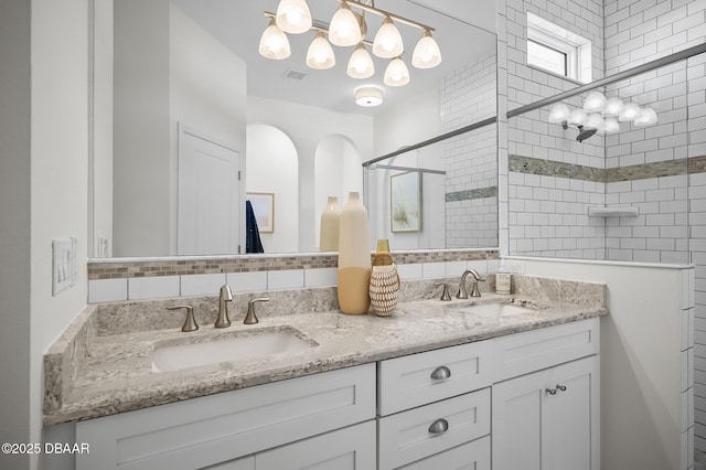 bathroom featuring tiled shower, vanity, and decorative backsplash