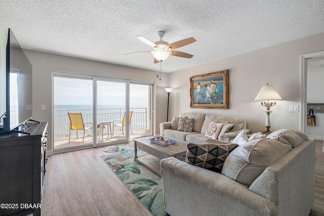 living room featuring a textured ceiling, ceiling fan, wood finished floors, and a wealth of natural light