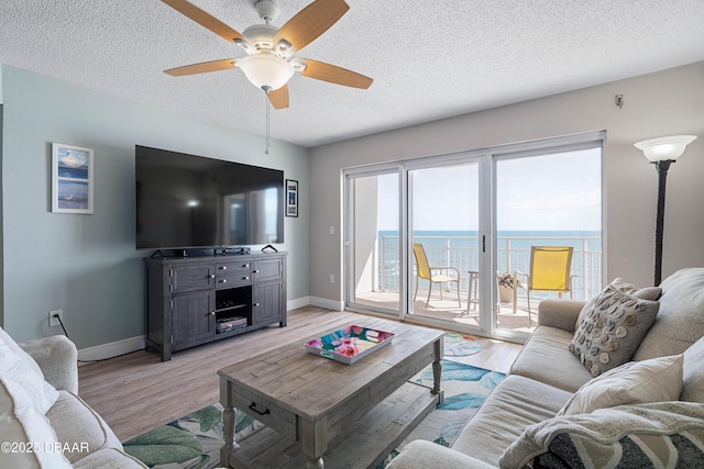 living room with baseboards, a ceiling fan, and light wood-style flooring