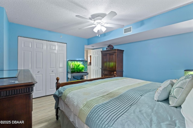bedroom featuring a textured ceiling, a closet, light wood-style flooring, and visible vents