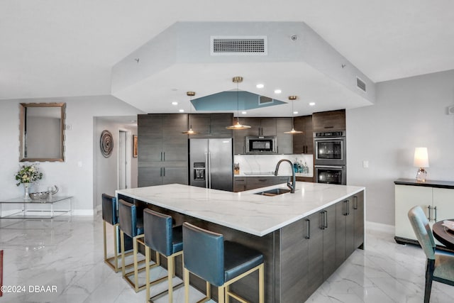 kitchen featuring sink, appliances with stainless steel finishes, backsplash, decorative light fixtures, and a spacious island