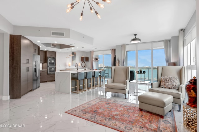 living room with a chandelier, a water view, and sink