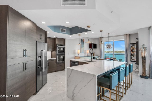 kitchen with stainless steel appliances, sink, a water view, pendant lighting, and a large island