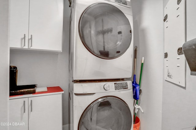 washroom with stacked washer / drying machine and cabinets