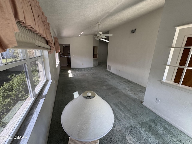 living area with dark colored carpet, visible vents, lofted ceiling, and a textured ceiling