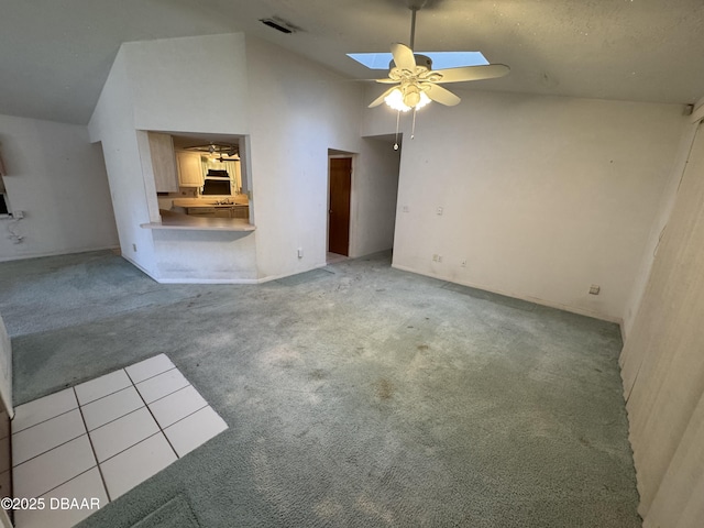 unfurnished living room with high vaulted ceiling, light colored carpet, a skylight, a ceiling fan, and visible vents