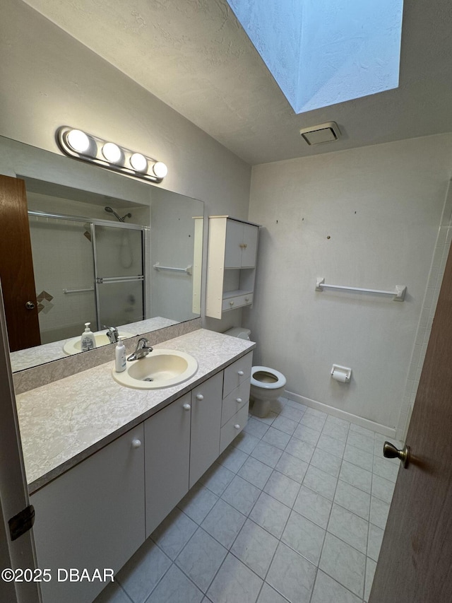 full bathroom featuring a skylight, toilet, vanity, baseboards, and tile patterned floors