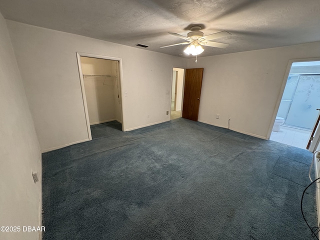 unfurnished bedroom featuring a textured ceiling, visible vents, baseboards, a closet, and dark carpet