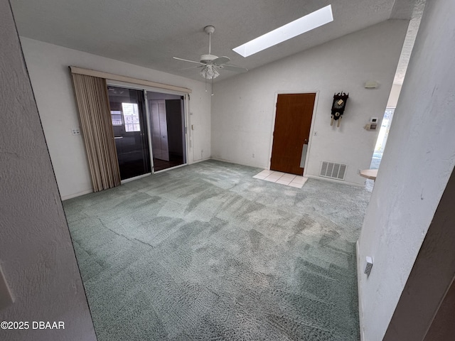 unfurnished room with vaulted ceiling with skylight, light colored carpet, ceiling fan, and visible vents