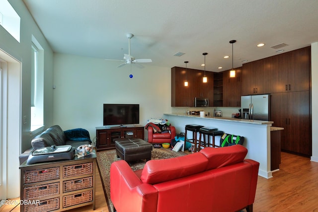 living room featuring ceiling fan and light hardwood / wood-style flooring