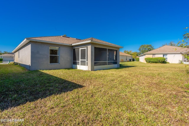 rear view of house with a sunroom and a yard