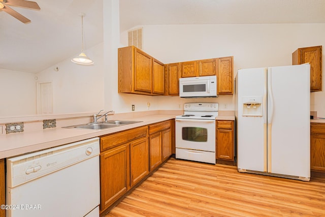 kitchen featuring lofted ceiling, white appliances, sink, hanging light fixtures, and light hardwood / wood-style floors