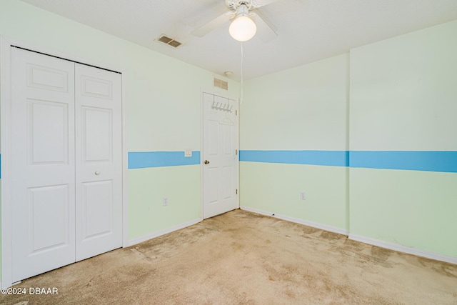 unfurnished bedroom with ceiling fan, a closet, and carpet