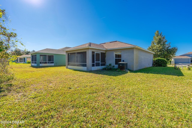 back of property featuring a lawn, a sunroom, and central AC unit