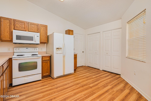 kitchen featuring lofted ceiling, light hardwood / wood-style floors, white appliances, and a textured ceiling