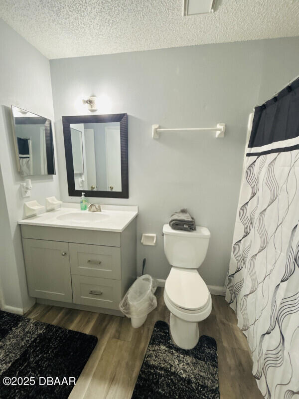 bathroom with hardwood / wood-style flooring, vanity, a textured ceiling, and toilet