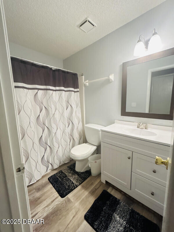 bathroom with hardwood / wood-style flooring, vanity, toilet, and a textured ceiling