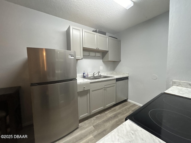 kitchen featuring gray cabinets, appliances with stainless steel finishes, sink, and light wood-type flooring