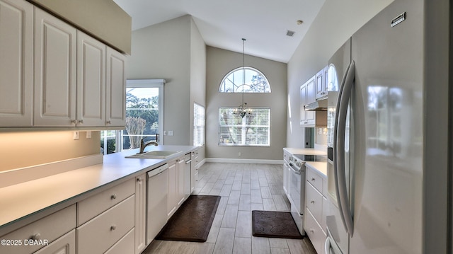 kitchen featuring sink, white cabinetry, high vaulted ceiling, hanging light fixtures, and white appliances