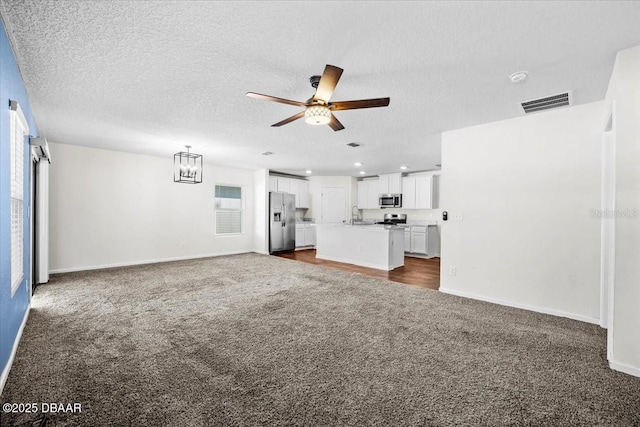 20 Sand Wedge Ln, Bunnell, FL 32110 - unfurnished living room with dark colored carpet, ceiling fan, a chandelier, baseboards, and a textured ceiling