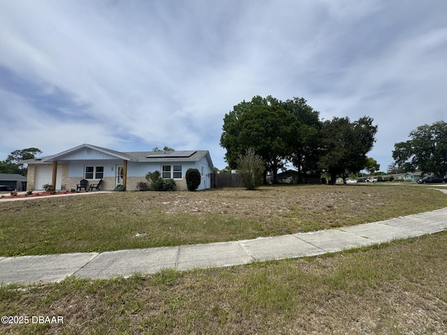 view of front facade with solar panels, a front yard, a garage, brick siding, and fence