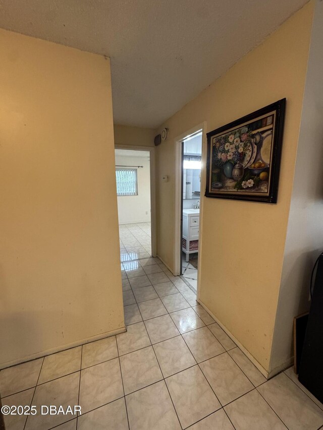 hallway featuring a sink and light tile patterned flooring