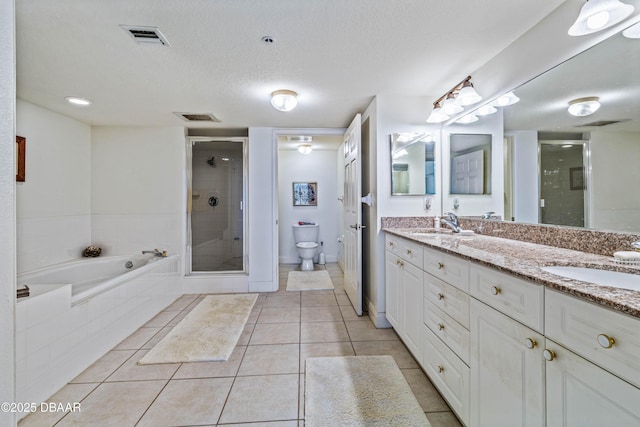 bathroom featuring a stall shower, toilet, double vanity, a garden tub, and tile patterned floors