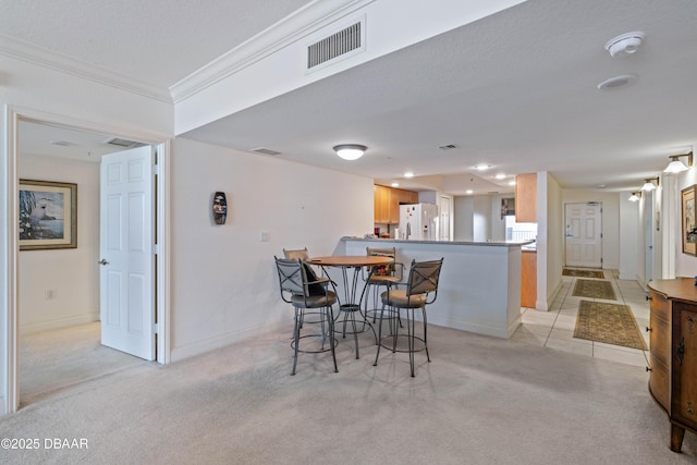 dining room with ornamental molding, baseboards, light colored carpet, and recessed lighting