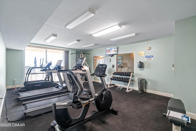 gym featuring baseboards and a textured ceiling