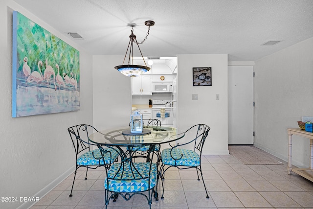 dining space with a textured ceiling and light tile patterned flooring