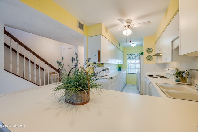 kitchen with white electric stove, kitchen peninsula, sink, and white cabinets