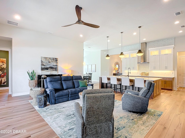 living room with light wood finished floors, visible vents, and recessed lighting