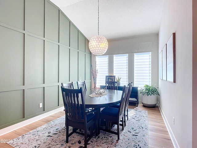 dining room with baseboards, light wood-style floors, and a decorative wall