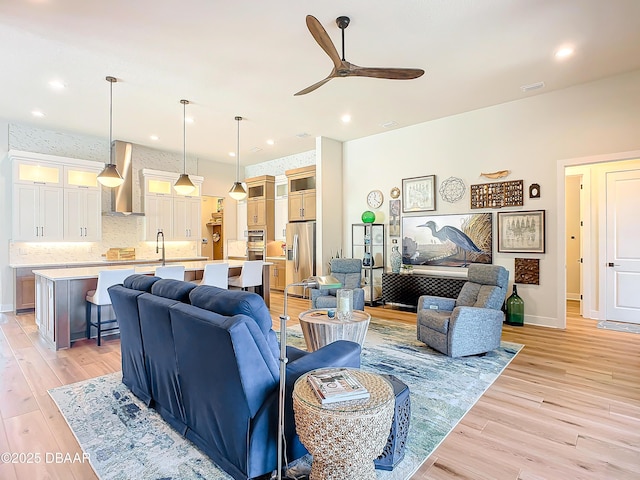 living room with baseboards, recessed lighting, a ceiling fan, and light wood-style floors