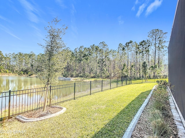 view of yard with a water view, a forest view, and a fenced backyard