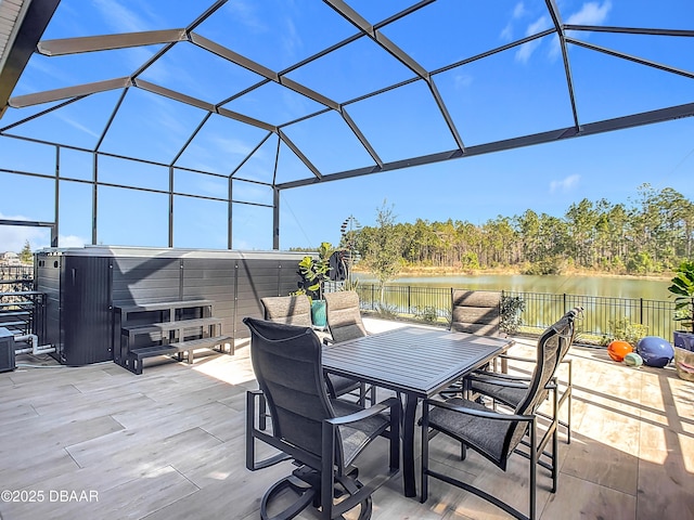 view of patio / terrace with a lanai, a jacuzzi, a water view, fence, and outdoor dining space