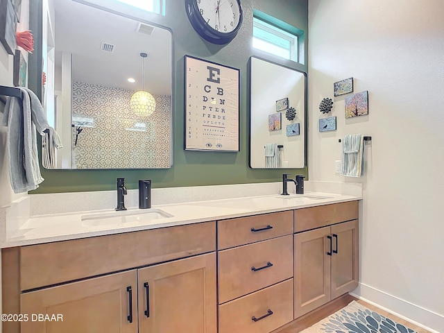 bathroom with double vanity, baseboards, visible vents, and a sink