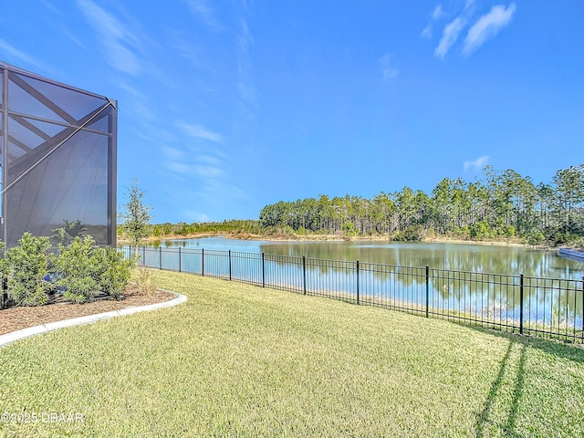 view of yard featuring a water view, glass enclosure, and fence