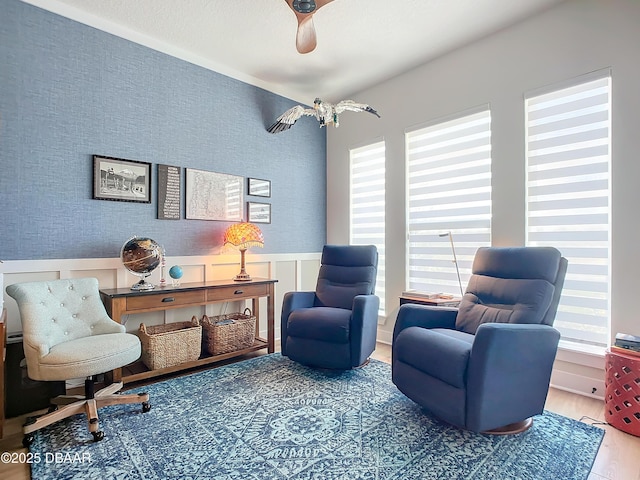 sitting room featuring wainscoting, wallpapered walls, and wood finished floors