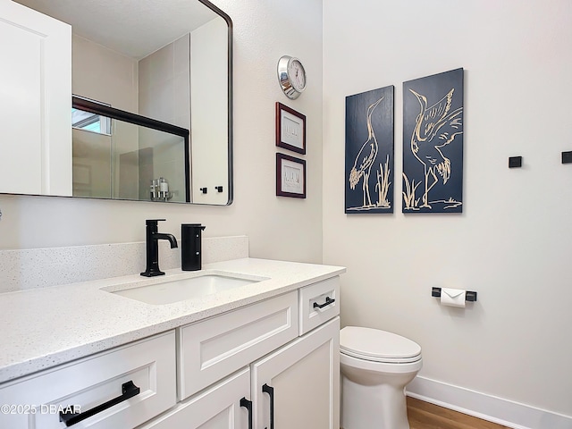 full bath with baseboards, toilet, vanity, and a shower stall