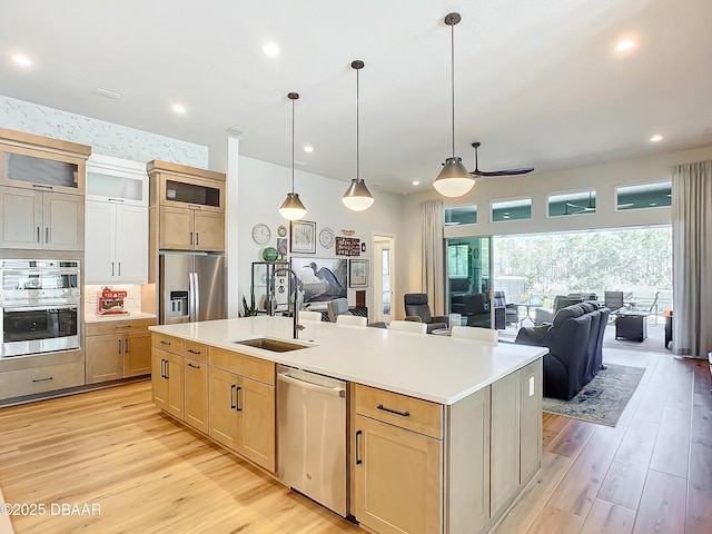 kitchen with appliances with stainless steel finishes, open floor plan, a kitchen island with sink, and a sink