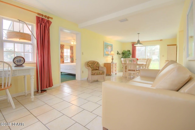 living room featuring beamed ceiling, light tile patterned floors, and a wealth of natural light